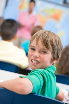 Student in class looking at camera with teacher in background (selective focus) Stock Photos