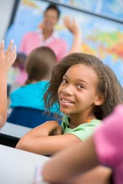 Student in class looking at camera with teacher in background (selective focus) Stock Photos