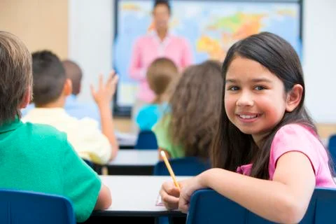 Student in class looking at camera with teacher in background (selective focus) Stock Photos