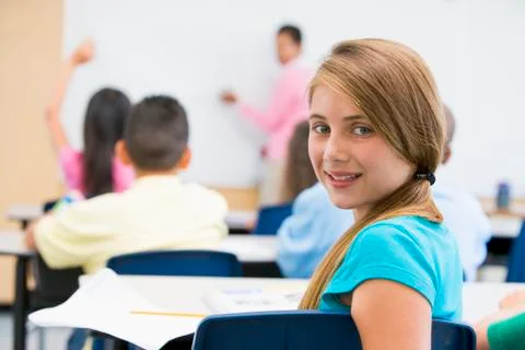 Student in class looking at camera with teacher in background (selective focus) Stock Photos