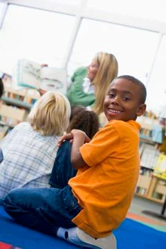 Student in class looking at camera with teacher reading in background (selective Stock Photos