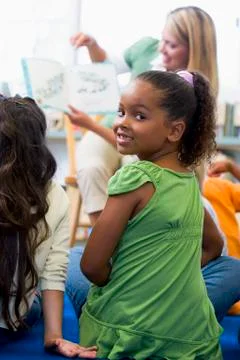 Student in class looking at camera with teacher reading in background (selective Stock Photos