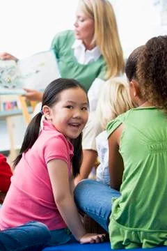 Student in class looking at camera with teacher reading in background (selective Stock Photos