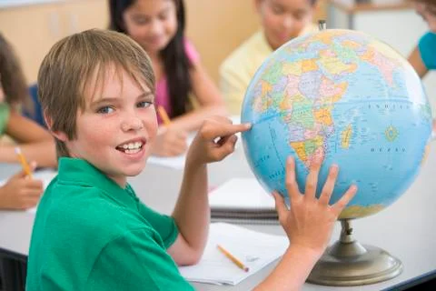 Student in class pointing at globe with students in background (selective focus) Stock Photos