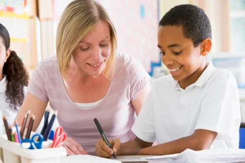 Student in class taking notes with teacher helping Stock Photos