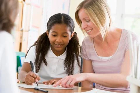 Student in class taking notes with teacher helping Stock Photos
