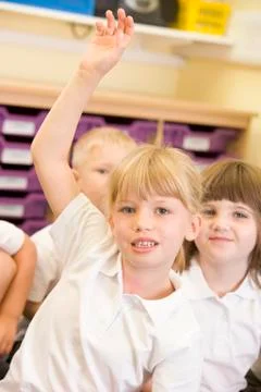 Student in class volunteering with students in background (selective focus) Stock Photos