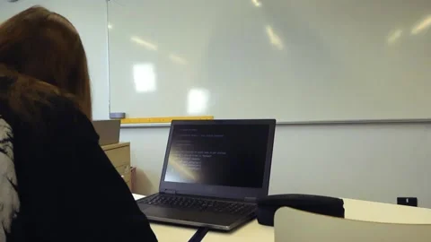 Student coding on a laptop in a classroom with an AI running Stock-Footage 344859821