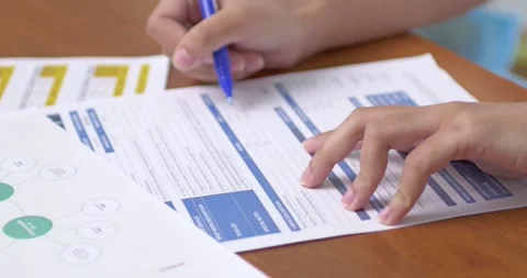 Student completing academic paperwork at desk classroom environment document Stock Footage 313938209