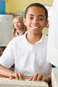 Student at computer terminal typing with student in background (selective focus) Stock Photos