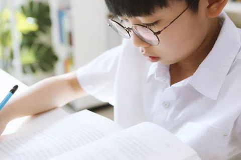 A student concentrating on studying while looking at a book and a boy reading Stock Photos
