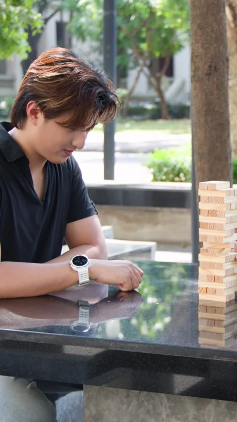 Student Concentrating While Playing Wooden Block Tower Game Outdoors Stock Footage 337867260