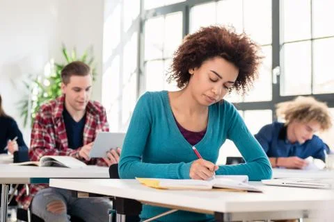 Student concentrating while writing an essay during class in an 스톡 사진
