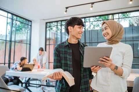 Student couple chatting and using a pad Stock Photos
