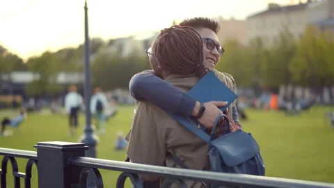 Student couple having break hugging and talking outdoors in college campus Stock Footage 141191181