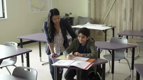 Student at desk talking to teacher in classroom Stockbeeldmateriaal 221034358