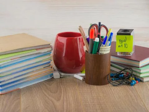 Student desktop, stack books, accessories, stationery, red mug, crayons Stock Photos