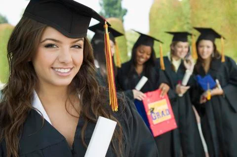 Student With Diploma While Friends Standing In Background At University Stock Photos