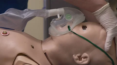 Student doctor using oxygen mask on simulation baby doll, close-up Vidéo 142605777