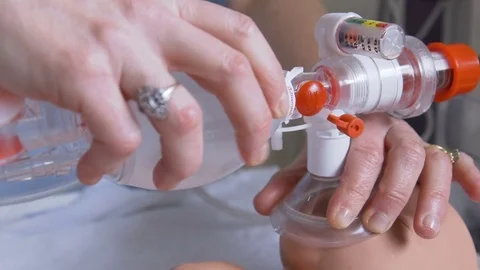 Student doctor using stethoscope and oxygen mask on baby doll Stock Footage 85369341