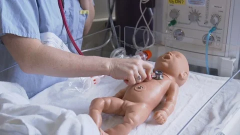 Student doctor using stethoscope and oxygen mask on baby doll Stock-Footage 85369568