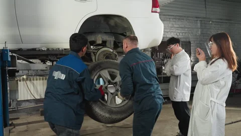 Student Documenting Mechanics Fixing Car in Auto Repair Workshop Stock Footage 303065870
