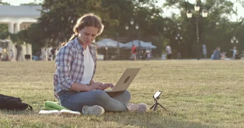 Student does homework looking into book and typing on laptop Stockbeeldmateriaal 154321304