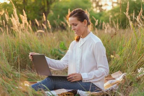 A student does homework online sitting on the beach in a field Stock Photos