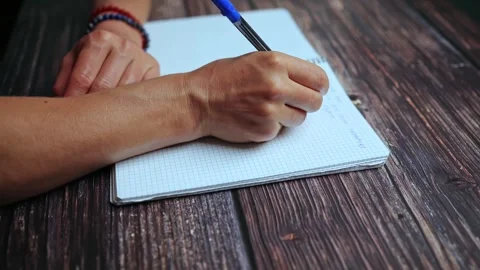 The student is doing her homework, writing notes in a notebook. On the wooden Stock Footage 243291128