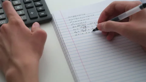 A student doing math in a notebook using a calculator. Stock Footage 307355501