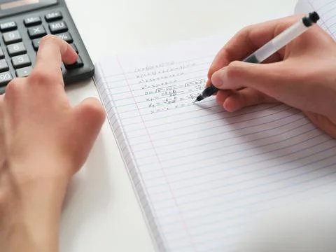 A student doing math in a notebook using a calculator. Close up. Foto stock