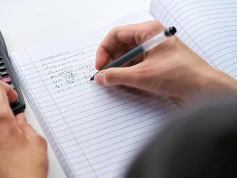 A student doing math in a notebook using a scientific calculator. Close up. Foto stock