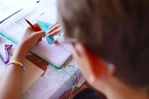 Student drawing a triangle with a ruler and a pencil in a notebook during m.. Stock Photos