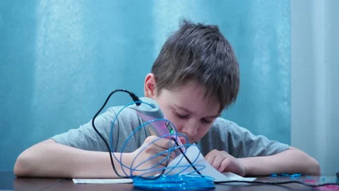 A student draws with a 3D pen. raises his face and smiles at the camera and Stock Footage 146304537