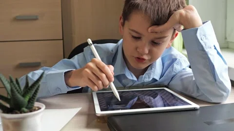 A student draws on a graphic tablet. a boy in a blue shirt learns to draw Stock Footage 168943140