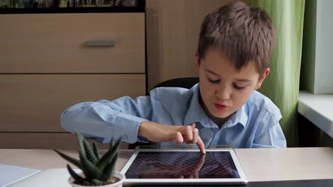 A student draws on a graphic tablet. a boy in a blue shirt is studying at the Stock Footage 170148763