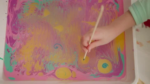 Student draws smiling face on oily water surface with paint Stock Footage 172364762