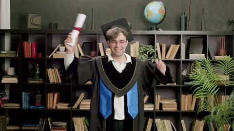 Student dressed in black robe with cap on head joyfully and proudly raises hands Stock Footage 316092650