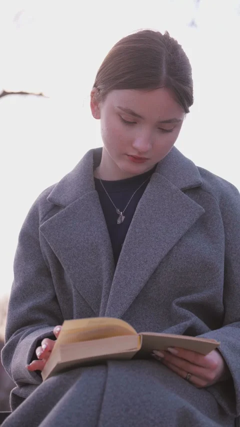 Student drinking coffee and reading a book on a bench Vidéo 309782222