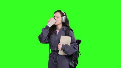 Student drinking coffee while listening music, holding book on the chroma key Stock Photos