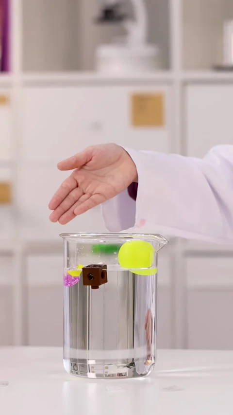 Student Dropping Small Cube into Beaker for Science Experiment Stock-Footage 344518431