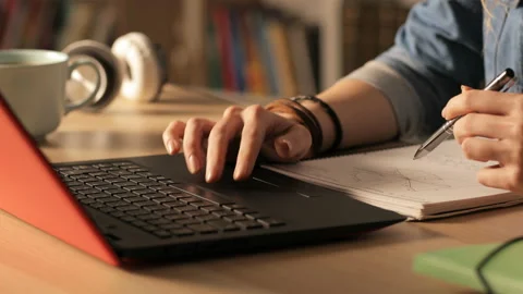 Student e-learning on laptop with notes at home at night Stock Footage 127993559