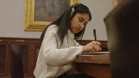 Student engaged in focused writing session at university library Stock Footage 312769546