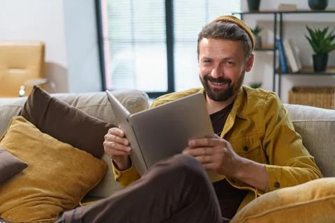 Student engaging in deceptive behavior sit on sofa and hold laptop like book Stock Photos