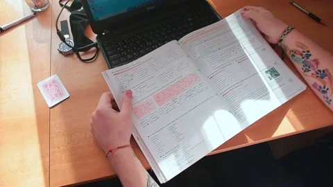 The student examines the study notes at the table. Focus on paper information Video stock 149624272