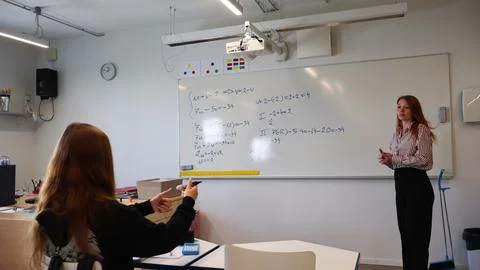 Student explaining math problems on classroom whiteboard to teacher Stock-Fotos