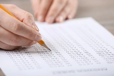 Student filling answer sheet at table, closeup Stock Photos