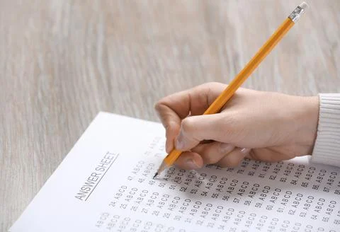 Student filling answer sheet at table, closeup Stock Photos