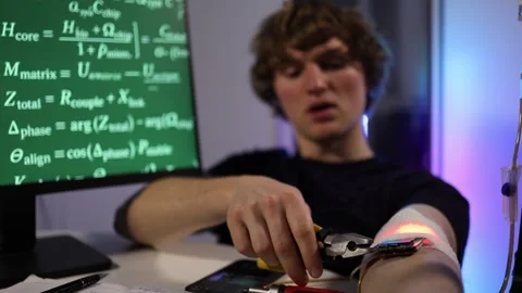 Student fine tunes wearable device during biohacking research Stock Footage 324444047