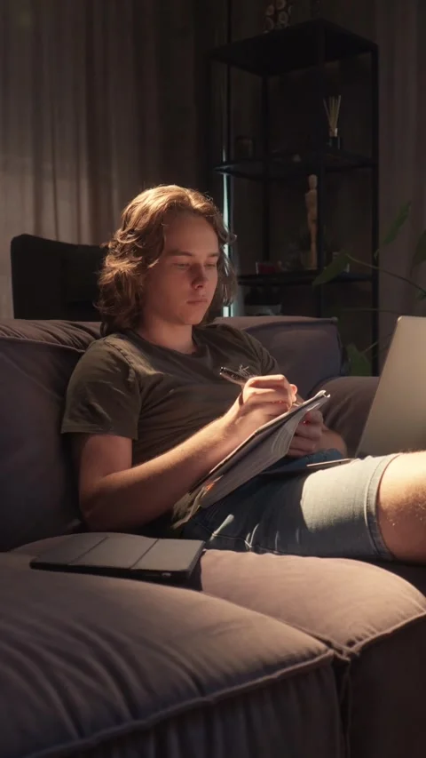 Student finishes taking notes and starts typing an essay on his laptop Stock Footage 310739269
